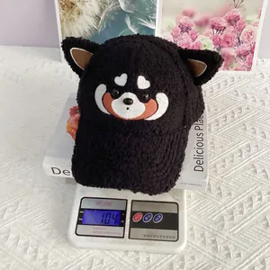 Gros plan d'une casquette noire en peluche avec oreilles et broderie koala sur balance