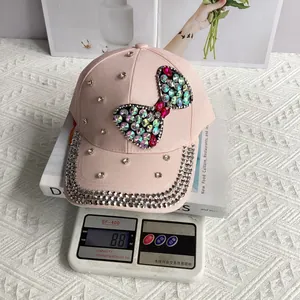 Close-up of a pink denim cap with rhinestone bow detailing, weighing 88g on a scale