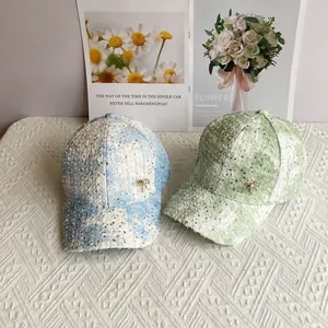 Detail of sequined baseball caps featuring small gold bows and pastel color blocking