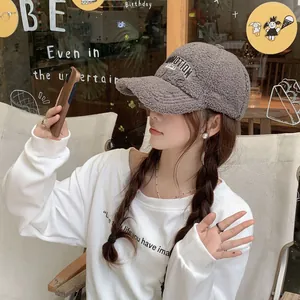 Detail of dark grey fleece baseball cap with white embroidery worn with white hoodie