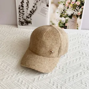 Dettaglio del cappellino in peluche cammello con fiocco dorato e perla raffinata