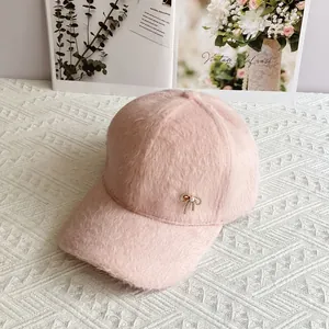 Dettaglio cappello baseball rosa in peluche con fiocco dorato e ciondolo di perle
