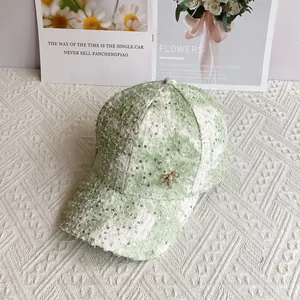 Detail of light green tweed baseball cap with silver sequins and golden bow accessory