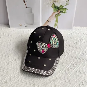 Detail of a black denim baseball cap with a large rhinestone bow and scattered crystals