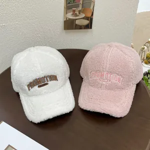 Winter plush baseball caps with embroidery in pink and white on a wooden surface