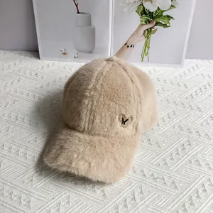 Detail of plush beige baseball cap featuring a delicate metal butterfly ornament