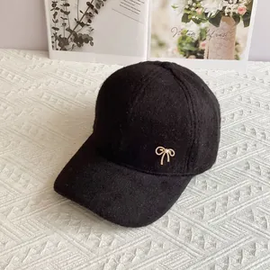 Dettaglio del berretto in lana nera con fiocco dorato e perla decorativa chic
