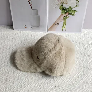 Detailed view of plush beige baseball cap with metal butterfly accent on soft faux fur texture