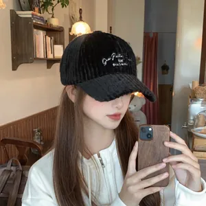 Close-up of black textured plush baseball cap with white positive letter embroidery