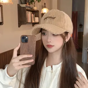 Detail of warm beige plush baseball cap with GOOD embroidery and soft corduroy texture