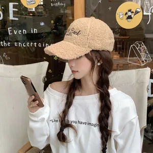 Close-up of embroidered 'Back' lettering on a beige faux shearling baseball cap