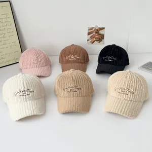 Detail of multi-color corduroy baseball caps with vintage letter embroidery in soft light