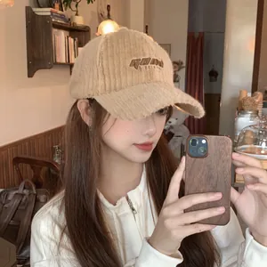 Detail of embroidered letters on warm beige plush corduroy baseball cap for women