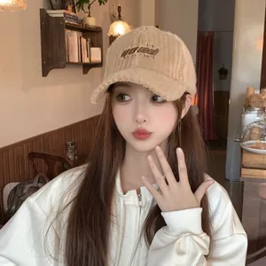 Detail of embroidered letters on warm beige plush baseball cap for autumn and winter