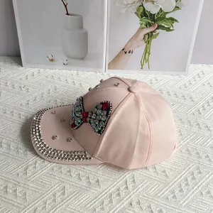 Detailed view of pink denim baseball cap featuring sparkling rhinestones and a bow