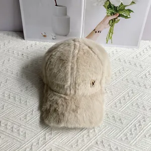 Detail of plush beige baseball cap featuring a delicate metal butterfly logo on soft fur