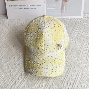 Detail of yellow and white sequins baseball cap with a gold bow pendant and frayed fabric