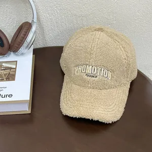 Detail of beige fleece baseball cap with PROMOTION embroidery on a wooden table