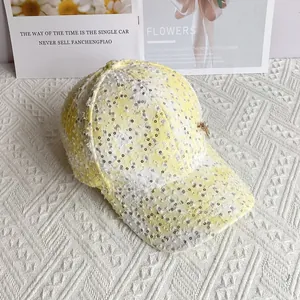 Detail of yellow tweed baseball cap with silver sequins and a small butterfly charm