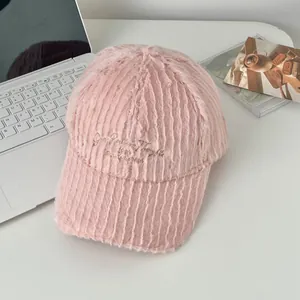 Close-up of pink fuzzy baseball cap with golden embroidery and plush ribbed texture