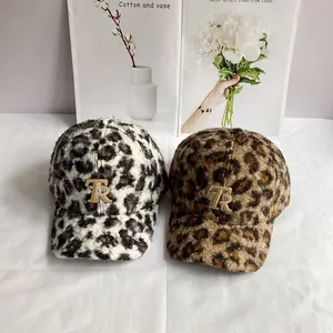 Macro shot of faux shearling leopard print baseball caps with metallic gold TR emblem