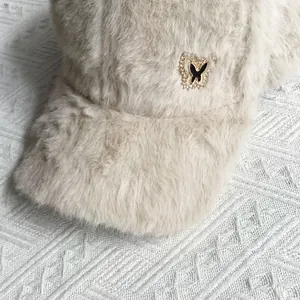 Detail of beige faux fur baseball cap featuring a sparkling rhinestone butterfly badge