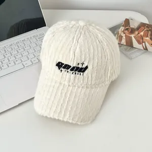 Detail of off-white plush baseball cap featuring black ROAD FRIENDLY embroidery and soft fur texture