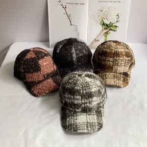 Detail of four colorful teddy velvet baseball caps in orange, brown, and grey plaid textures
