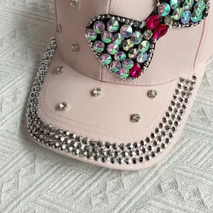 Detail of pink denim baseball cap featuring colorful rhinestone bow and sparkling studs