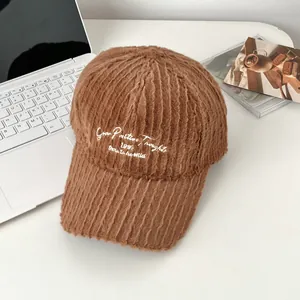 Detailed macro view of caramel brown plush baseball cap with white letter embroidery