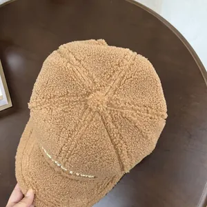 Detail of plush brown teddy fleece baseball cap with pearl trim and pom-pom top