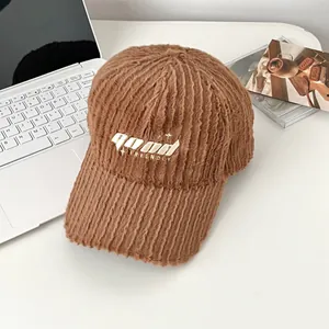 Close-up of brown plush texture baseball cap with GOOD embroidery on a cozy desk