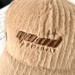 Macro shot of embroidered letters on soft light brown faux fur texture of the baseball cap