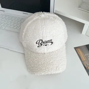 Close-up of white fleece baseball cap featuring dark Balance embroidery and soft texture