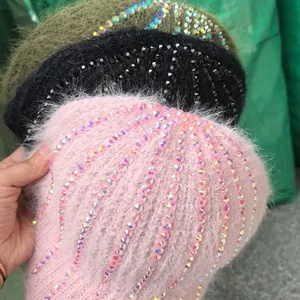 Dettaglio di berretti in maglia rosa, nero e verde con decorazioni di strass scintillanti