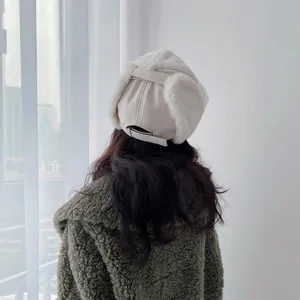 Detail of cream plush earflap hat with adjustable buckle on a warm winter coat