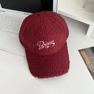 Close-up of burgundy sherpa baseball cap featuring white Balance embroidery and butterfly