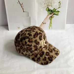 Close-up of leopard print teddy fleece texture and golden metal R logo on winter cap