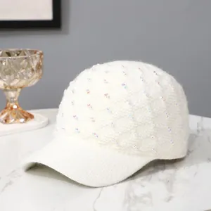 Elegant white knitted baseball cap with sparkling sequins on a marble background