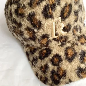 Macro detail of leopard print baseball cap featuring gold TR embroidery and fuzzy texture