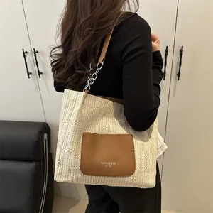 Straw woven tote bag with brown leather pocket and chain strap for beach vacations