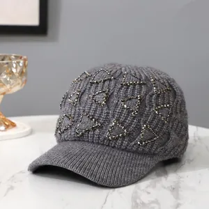 Detail der dunkelgrauen Strickmütze mit funkelndem Strass-Dreiecksmuster auf Marmor