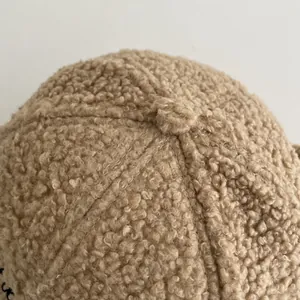 Close-up of beige sherpa fleece baseball cap showing textured top button and stitching