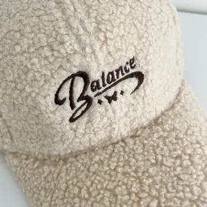 Close-up of beige faux shearling baseball cap featuring Balance embroidery and fuzzy texture