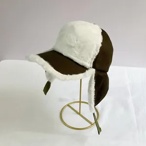 Close-up of brown windproof earflap hat with thick white faux fur lining on metal stand