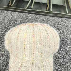 Dettaglio del cappello in maglia color crema con trama soffice e paillettes luccicanti