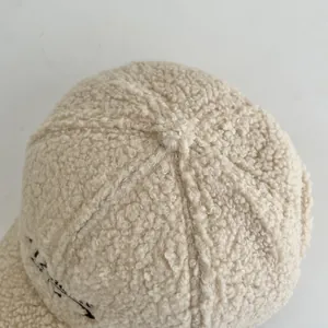 Detailed macro view of the cream white lamb wool texture and stitching on the baseball cap