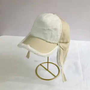 Detail of windproof beige trapper hat with white faux fur lining and ear flaps