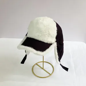 Detail of navy corduroy trapper hat with white faux fur lining on a golden stand