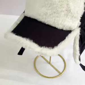 Detail of winter trapper hat with warm white faux fur lining on a gold stand